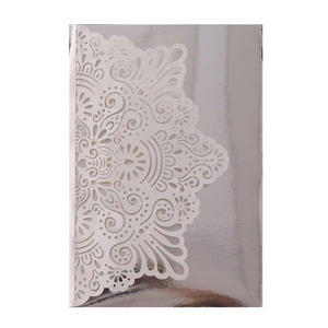 Detail of laser-cut lace pattern on ivory wedding invitation with metallic silver finish