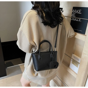 Close-up of black litchi texture leather crossbody bag with cute elephant charm detail