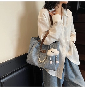 Detail of light blue floral tote bag with brown leather handles and pearl chain charm
