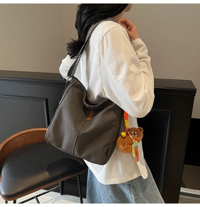 Détail du sac seau en toile grise avec breloque ours et cordelette de décoration