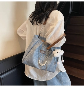 Detail of floral denim tote with leather chain strap and white cloud charm accessory