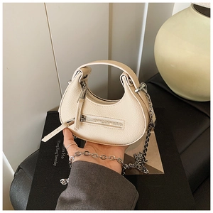 Detailed macro view of off-white lychee leather texture and silver zipper of crescent bag