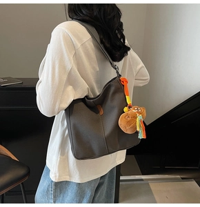 Gros plan du sac seau en toile gris foncé avec peluche d'ours et pompon tissé coloré