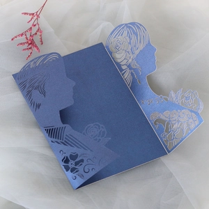 Close-up of navy blue laser-cut wedding invitation with pearl paper texture and silhouettes
