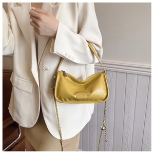 Detail of yellow leather crossbody bag with chain strap and metallic brand logo