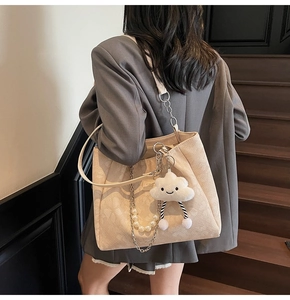 Detailed shot of beige tote bag with pearl chain strap and cute cloud charm on shoulder