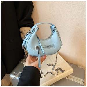 Close-up of light blue mini crescent bag with silver chain and textured leather detail