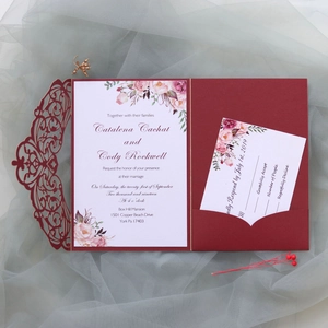 Detail view of burgundy laser-cut wedding invitation set with floral card on soft tulle