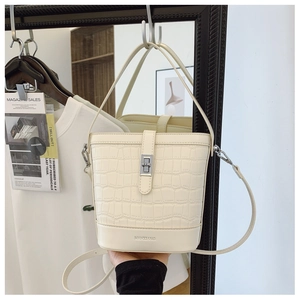 Detail of a cream bucket bag featuring crocodile texture and silver twist lock closure