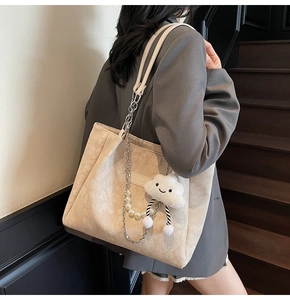 Detail of beige corduroy tote bag with pearl chain strap and plush cloud charm decor