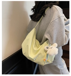 Vista laterale della borsa hobo a quadretti verde chiaro con ciondolo a coniglio in peluche