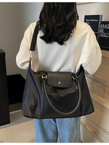 Grand sac cabas noir en nylon imperméable et cuir, porté par un mannequin en intérieur