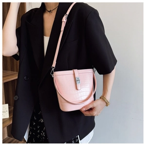 Detail shot of a pink crocodile-patterned bucket bag with silver metal rotating buckle closure