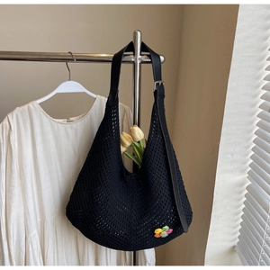 Close-up of black mesh knit hobo bag with rainbow flower patch and leather strap details