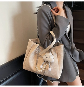 Detail of beige tote bag featuring floral texture, pearl chain and cloud charm