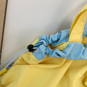 Detail of yellow nylon drawstring bag with light blue trim and black plastic cord lock