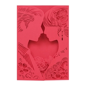 Close-up of laser-cut red wedding invitation featuring couple silhouette and floral lace