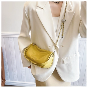 Detail of yellow mini pillow bag featuring silver chain strap and metal ball ornament