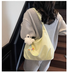 Rear view of a yellow canvas shoulder bag with textured surface and a plush star pendant