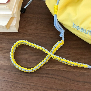 Close-up of yellow and blue woven strap and nylon fabric detail on a crossbody bag