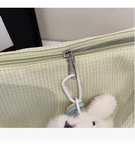 Dettaglio della cerniera su borsa tote a quadretti verde con ciondolo a forma di coniglio