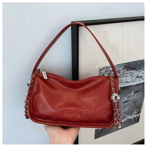 Detail of red leather bag texture with silver chain and CAHEKA brand logo embossing