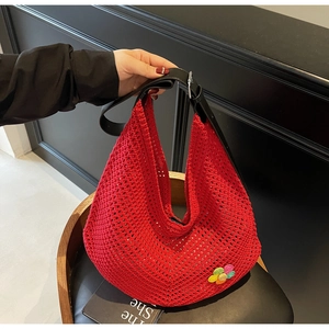Detail of red hollow knit tote bag featuring a floral patch and leather strap