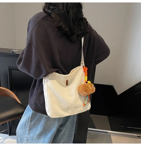 Détail du sac seau en toile blanche avec breloque ours en peluche et poignée tissée