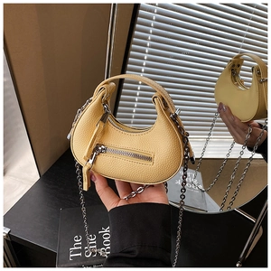 Detail view of yellow litchi leather mini half-moon bag with gold chain and top handle