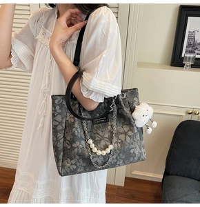 Detail of grey floral tote bag with pearl chain and cute white cloud charm accessory