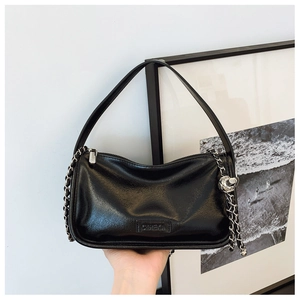 Detail of glossy black oil wax leather surface with brand embossing and silver hardware