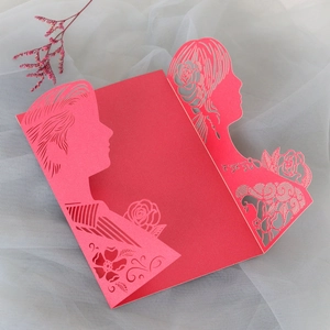 Close-up of red laser-cut wedding invitation featuring a romantic silhouette and roses