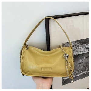 Detailed close-up of yellow leather handbag showing C&HEKA logo and silver chain metal hardware