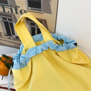 Detail view of yellow and light blue nylon drawstring tote bag with a dual-handle structure
