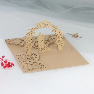Close-up of laser cut 3D wedding invitation with gold silhouette of couple and floral arch