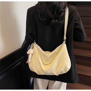 Detail of light yellow cloud shoulder bag with chain strap and teddy bear charm
