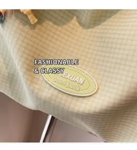 Detail of light green checkered canvas bag featuring a rubber XUEXUAN logo patch