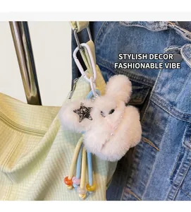 Dettaglio di un ciondolo a coniglio in peluche bianco con perle su borsa gialla
