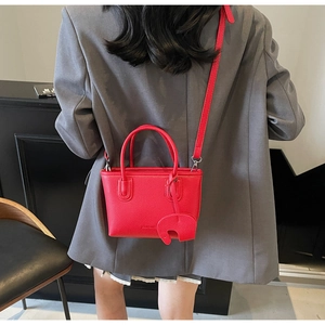 Red lychee pattern handbag with a cute elephant charm shown on a charcoal blazer