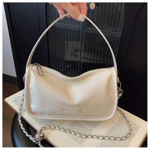 Detailed view of cream leather handbag with gold chain strap on an open book