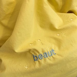 Macro view of water-resistant yellow nylon fabric with exquisite blue beaut embroidery