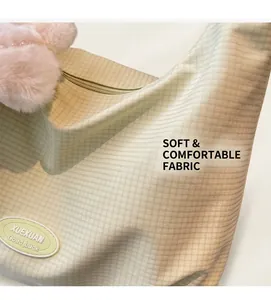 Close-up of light green waffle fabric shoulder bag with rubber label and plush pendant