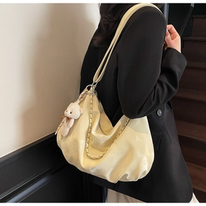 Detail of cream hobo tote bag featuring soft pleated leather and a cute bear charm