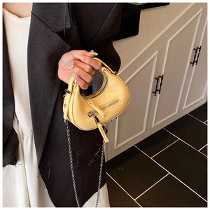 Close-up of bright yellow mini leather bag with metal chain strap and pebble texture