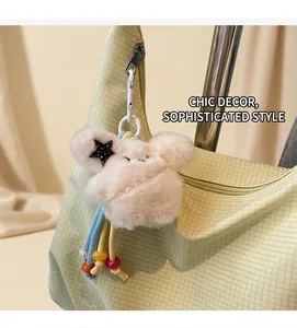Detail of white plush doll charm with pearl necklace on a green canvas shoulder bag