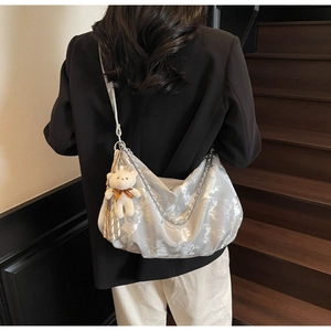 Detailed view of silver metallic tote bag with chic pleats and cute white bear charm