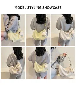 Dettaglio della grande borsa tote in tela con ciondolo di peluche indossata dal modello
