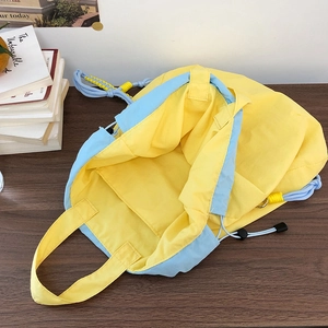 Detail of nylon bucket bag with yellow body, blue drawstring and internal storage pocket