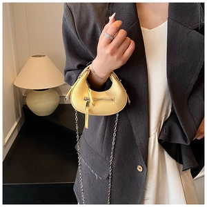Detail of mini yellow crescent bag with lychee leather texture and silver chain strap