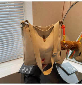 Détail du sac seau en toile beige avec écusson en cuir OZBG et breloque ours en peluche marron